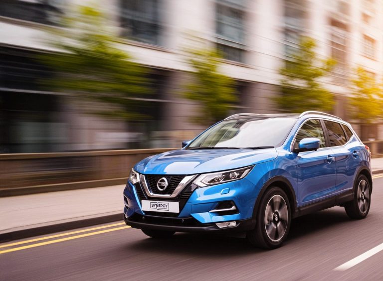 A blue SUV driving through a city, which is blurred in the background